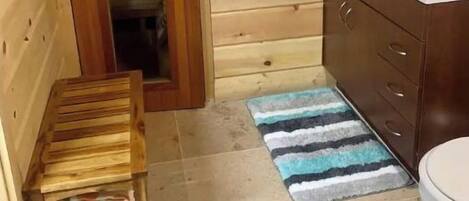 Un baño con paneles de madera, un banco de madera, un lavamanos y un inodoro.