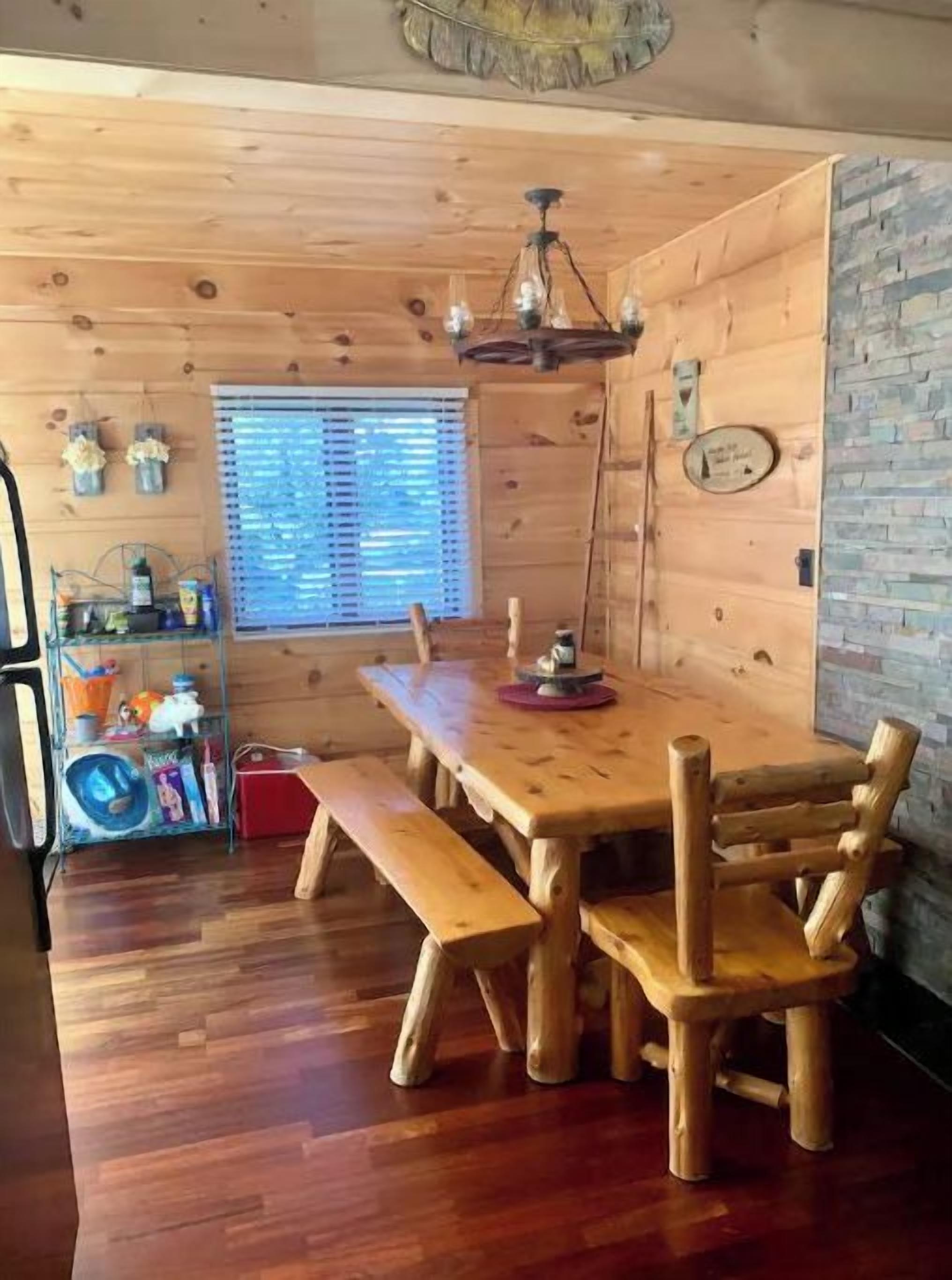 Un interior de madera con una mesa de comedor, bancos y una araña.