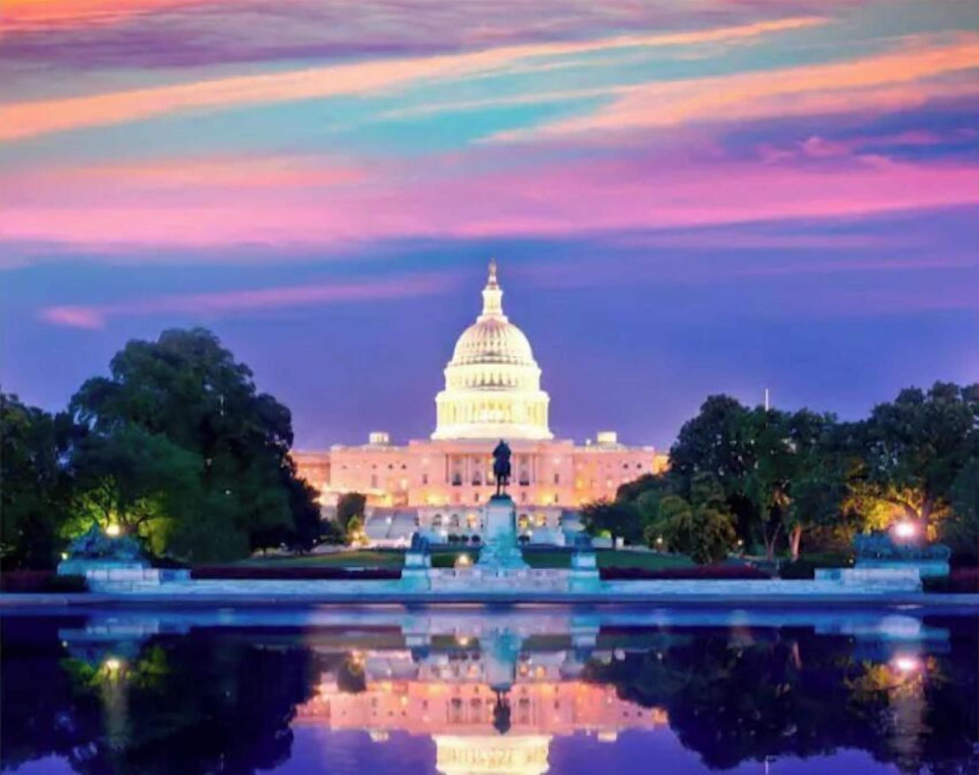 The United States Capitol building at twilight with a reflection in a water feature in front.