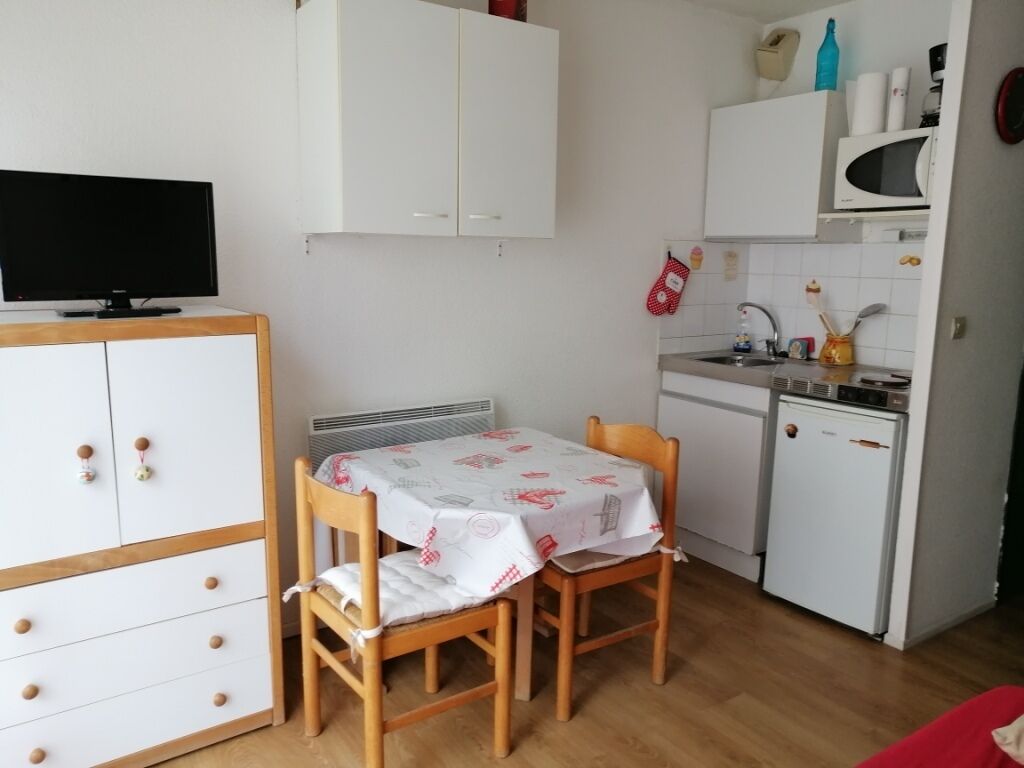 Cocina compacta con mesa, sillas, microondas y un refrigerador pequeño.
