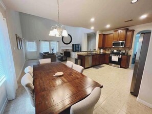 A spacious dining area with a wooden table and chairs, a kitchen with modern appliances, and a living room with a fireplace.