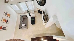 A modern living room with a staircase, a sofa, a coffee table, and a fireplace. - Spacious | Large Groups | Katy Mall, Parks! (Katy)
