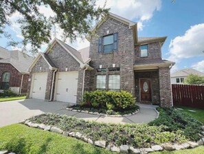 Stunning two-story home with a brick facade and gabled roof, featuring a front entrance with a door and small porch.