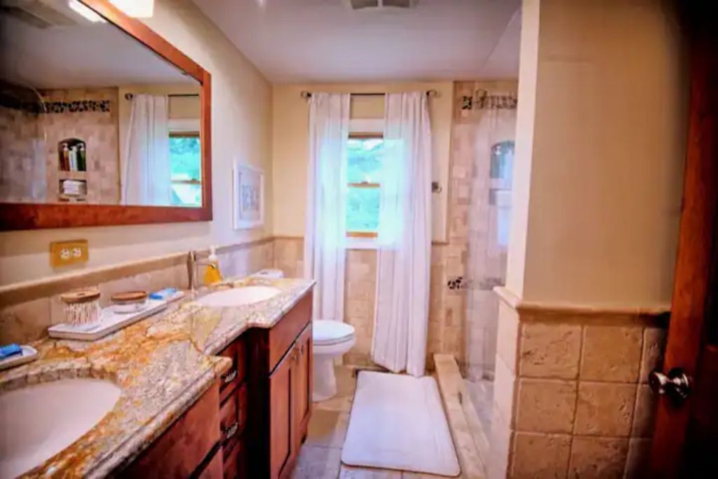 A bathroom with a marble vanity, a toilet, and a shower area.