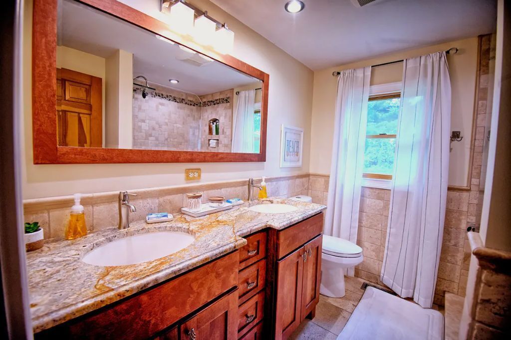Un bagno con doppio lavabo, un ampio specchio, un WC e zona doccia.