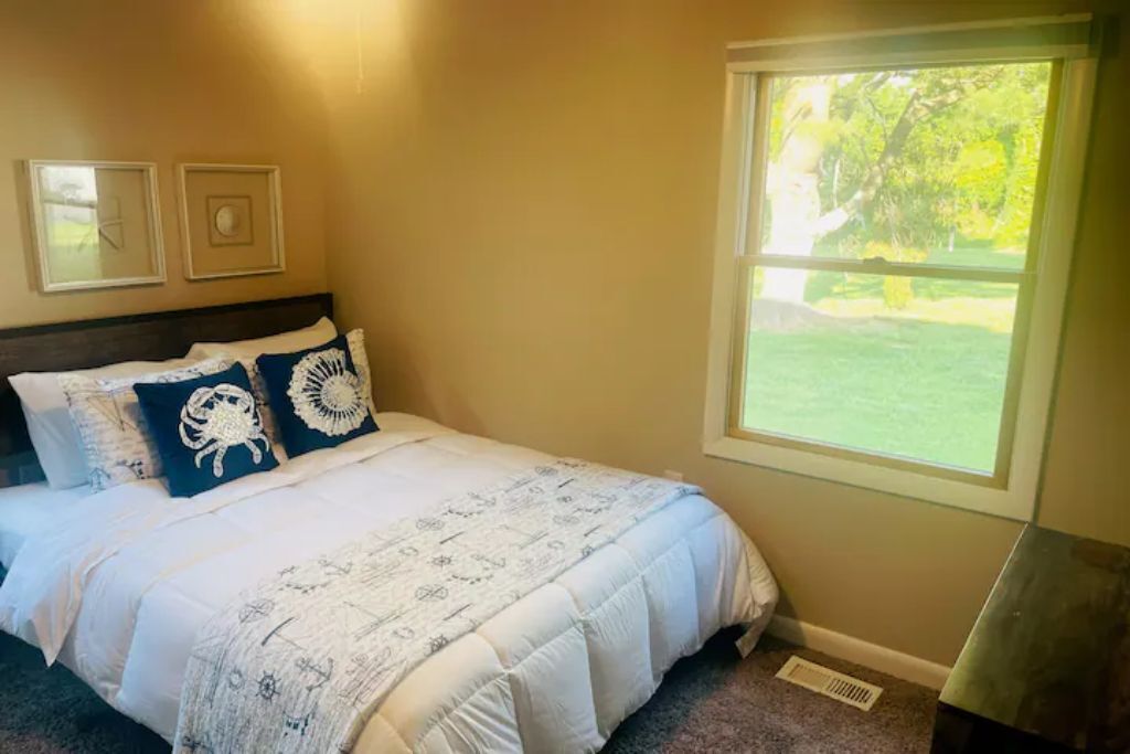 Une chambre à coucher avec un lit, une fenêtre et un mur orné de deux tableaux encadrés.
