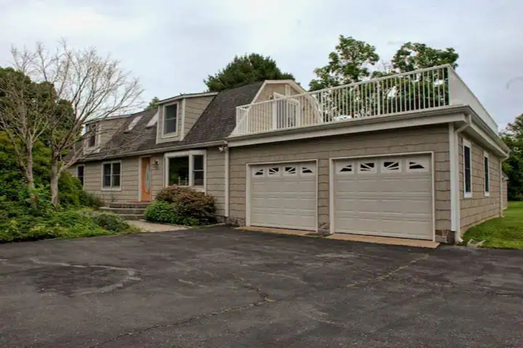 A two-story house with a front garage, a balcony with a railing, and a driveway.