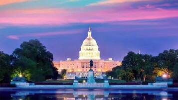 The United States Capitol building at twilight with a reflection in a water feature in front.