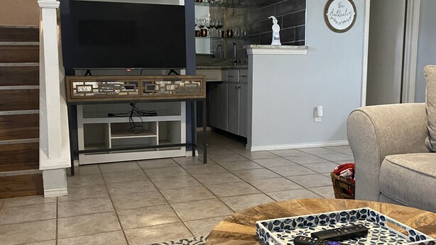 Een moderne woonkamer met een houten salontafel, een kamerkleed met dessin en een tv-meubel met een flatscreen televisie.