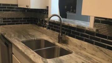 A kitchen with a double sink, a dishwasher, and a window above the sink.