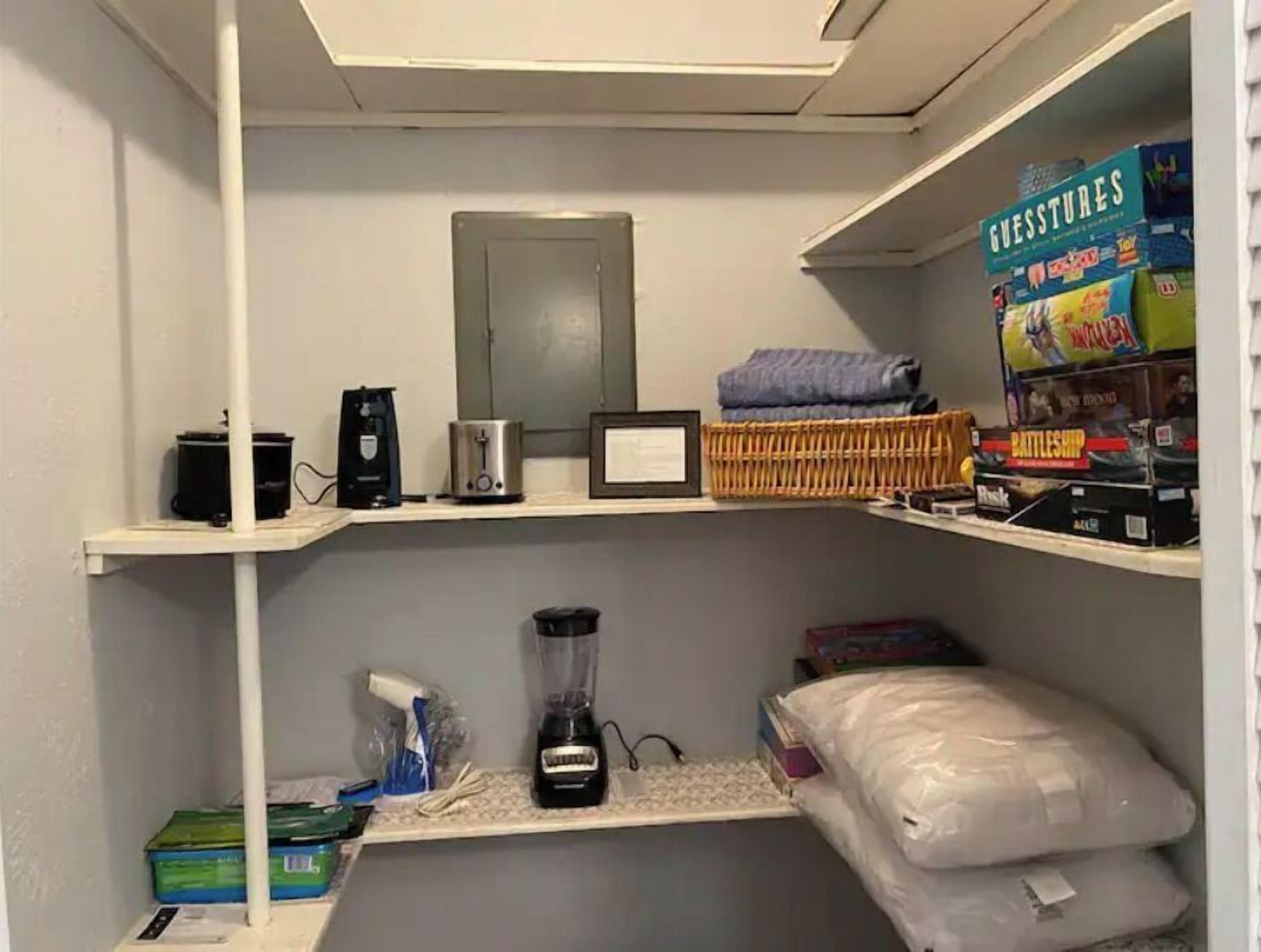 Un piccolo spazio contenitore con scaffali che ospitano diversi oggetti, tra cui una macchina da caffè, un frullatore e prodotti confezionati.