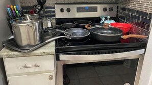 Een keuken met een fornuis, pannen, braadpannen en een magnetron.