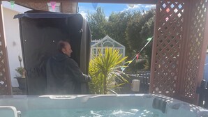Boblebad med en person stående i det, omgivet af et træhegn og plantekasser.