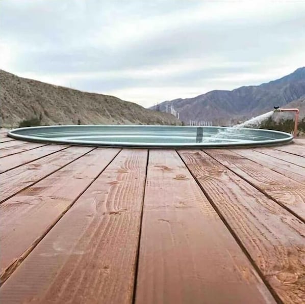 Un pontile in legno con una piscina circolare e un elemento d'acqua.