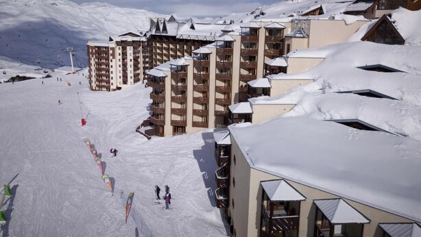 Ein schneebedecktes Skigebiet mit mehrstöckigen Gebäuden, Skipisten und einem klaren Himmel.