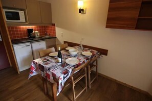 A compact kitchen with a microwave, coffee maker, and a dining table set with plates and a bottle. - 3rd floor, sauna, hammam, balcony, tv, 28m², Val Thorens (Val Thorens)