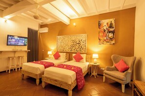 Habitación de hotel con dos camas, un televisor, un cuadro y una silla.