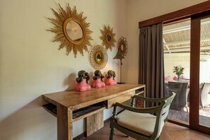 A room with a wooden desk, a green chair, and decorative wall mirrors.