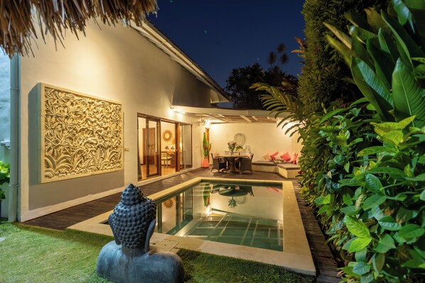 A modern house with a swimming pool, a decorative wall, and a dining area.