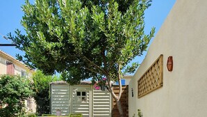 Een tuin met een boom, een kleine schuur en een houten omheining.