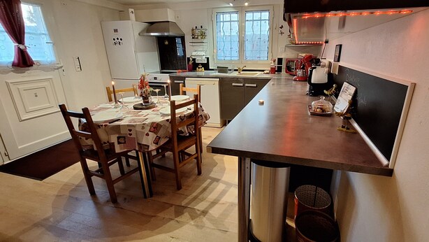 Een moderne keuken met een eethoek, inclusief een centraal eiland, inbouwapparatuur en een groot raam.