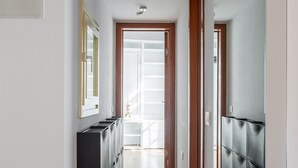 Un pasillo con suelo de madera, un mueble negro para guardado y una pared espejada.