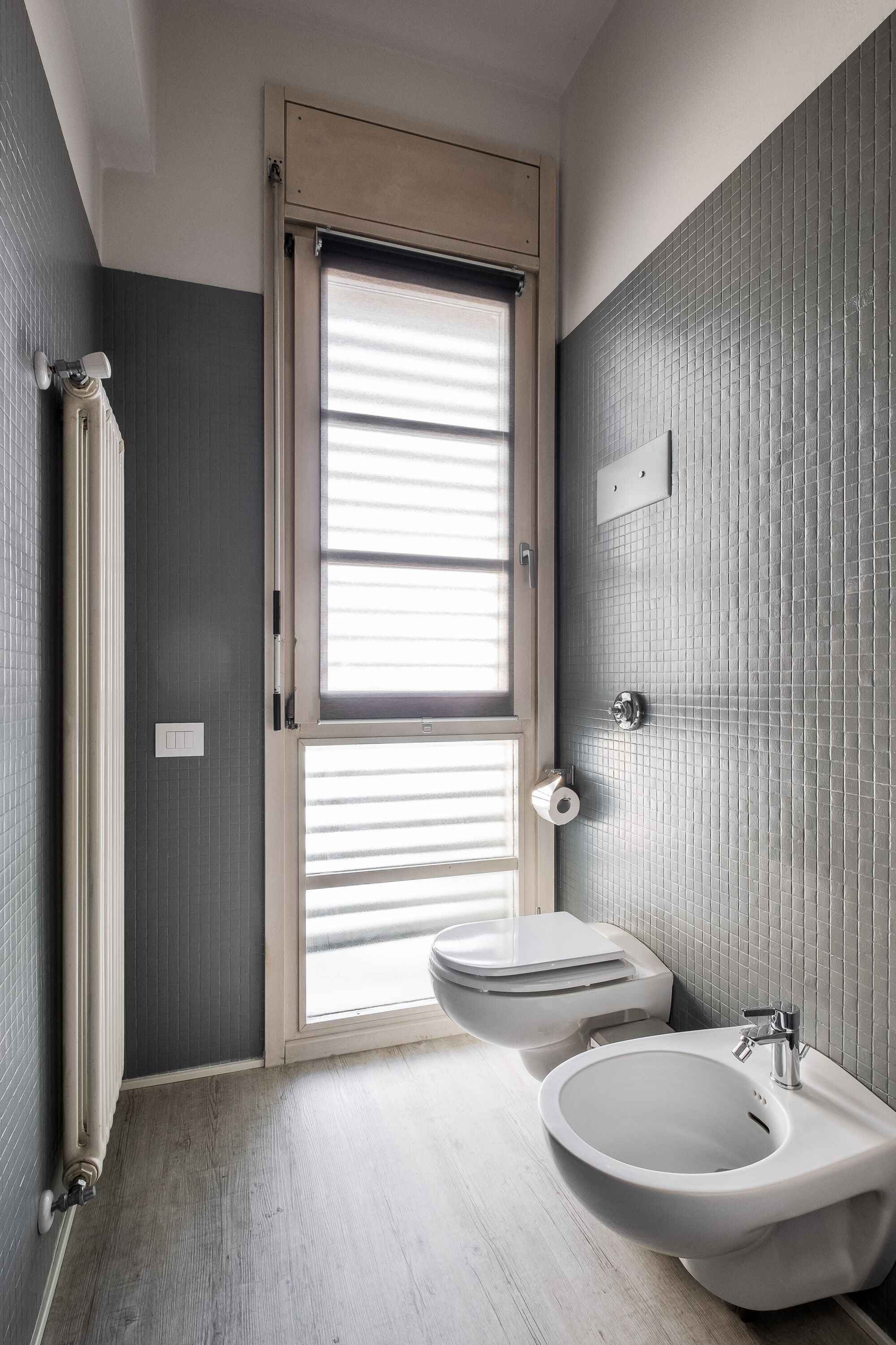 Une salle de bain moderne équipée d’un bidet, de toilettes et d’une fenêtre avec stores.