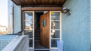 Una puerta de madera que da a una escalera, un letrero de circuito cerrado de televisión y una pared de azulejos.