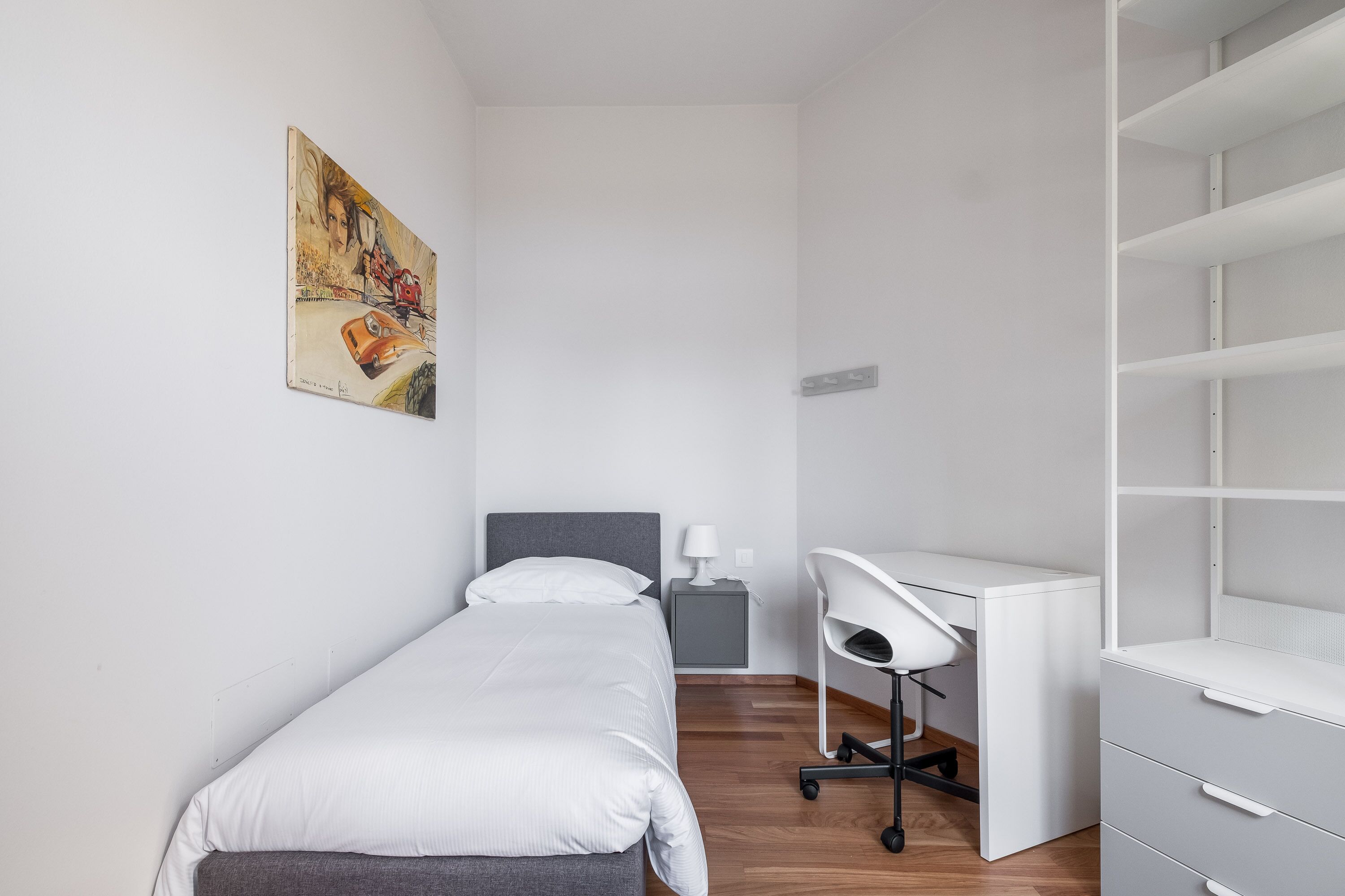 Ein kleines, modernes Schlafzimmer mit einem Einzelbett, einem Schreibtisch und einem Stuhl.