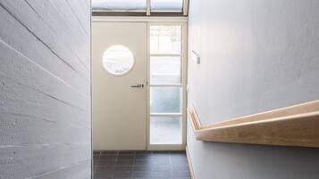 Uma escada estreita com corrimão de madeira e uma porta no topo.
