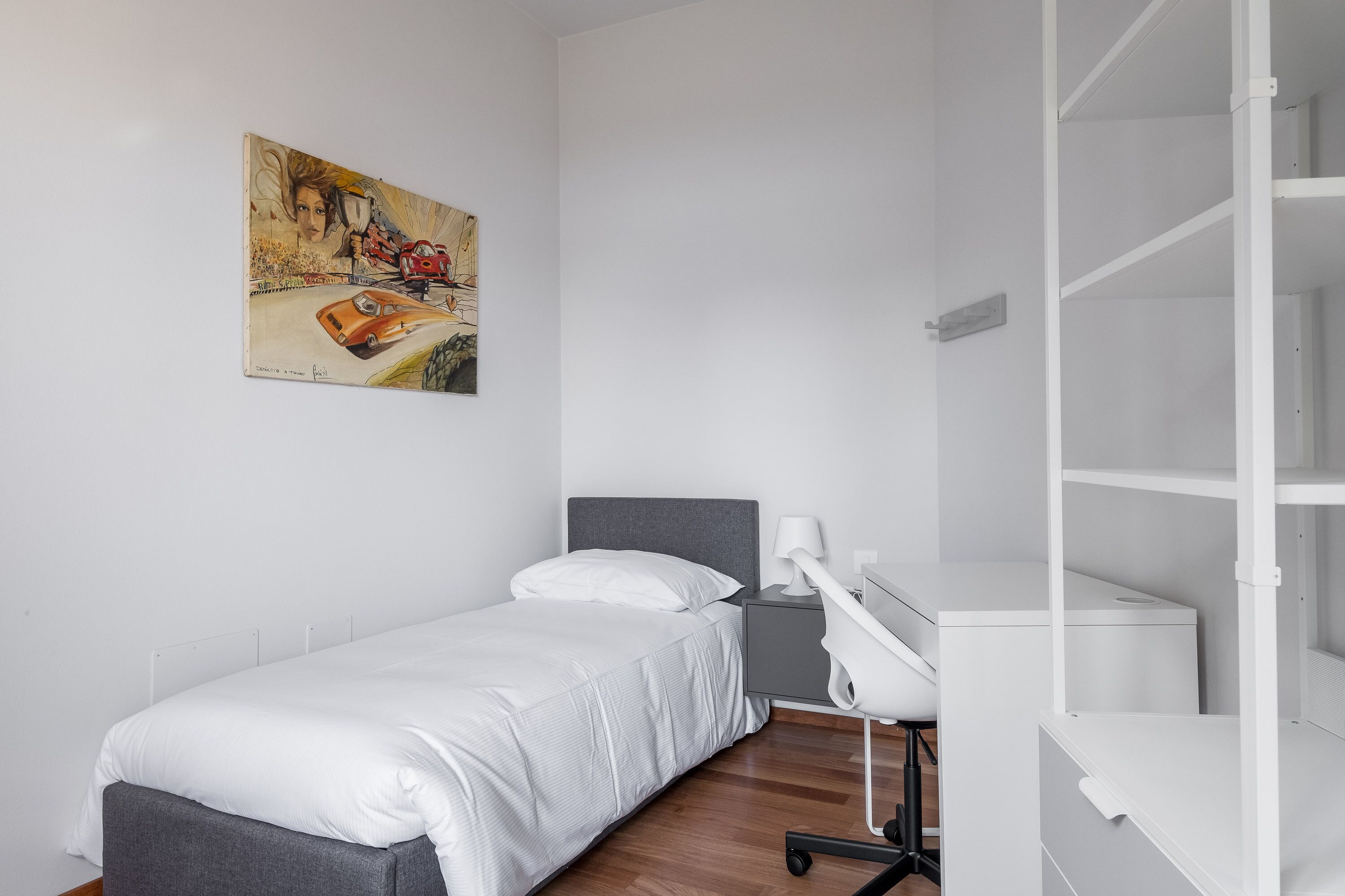 Une chambre à coucher avec un lit, une table de chevet, une lampe et un tableau au mur.