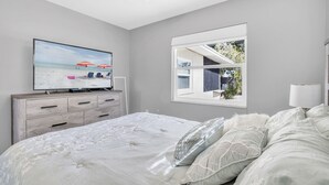 Een slaapkamer met een bed, een televisie, een raam en een dressoir.