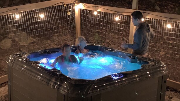 Een bubbelbad met een stenen muur en sfeerverlichting op de achtergrond.