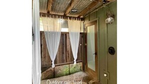 Ducha exterior bajo la lluvia, con paredes de madera y suelo de piedra.