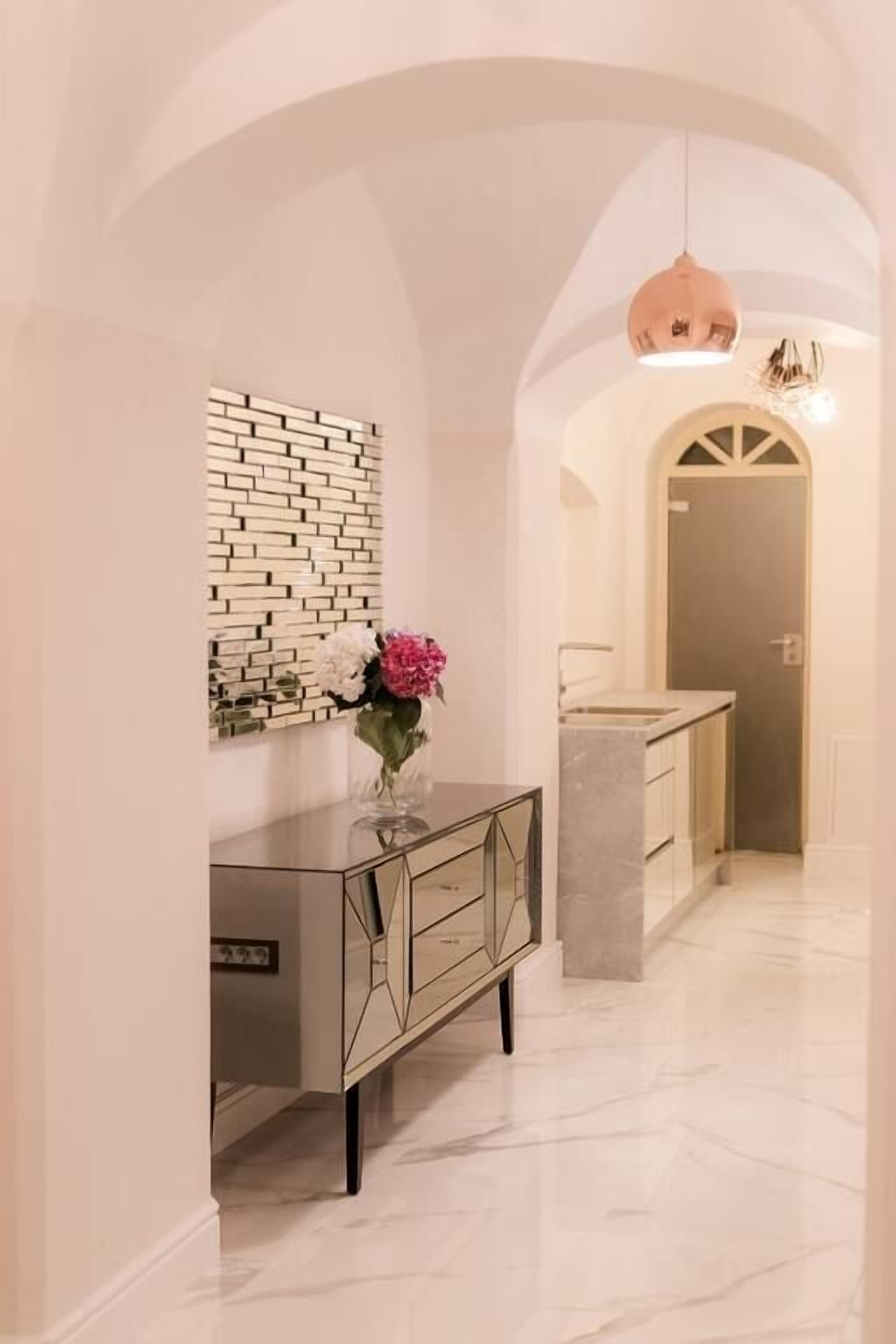 Un pasillo con un tocador moderno, un revestimiento decorativo y un techo abovedado.