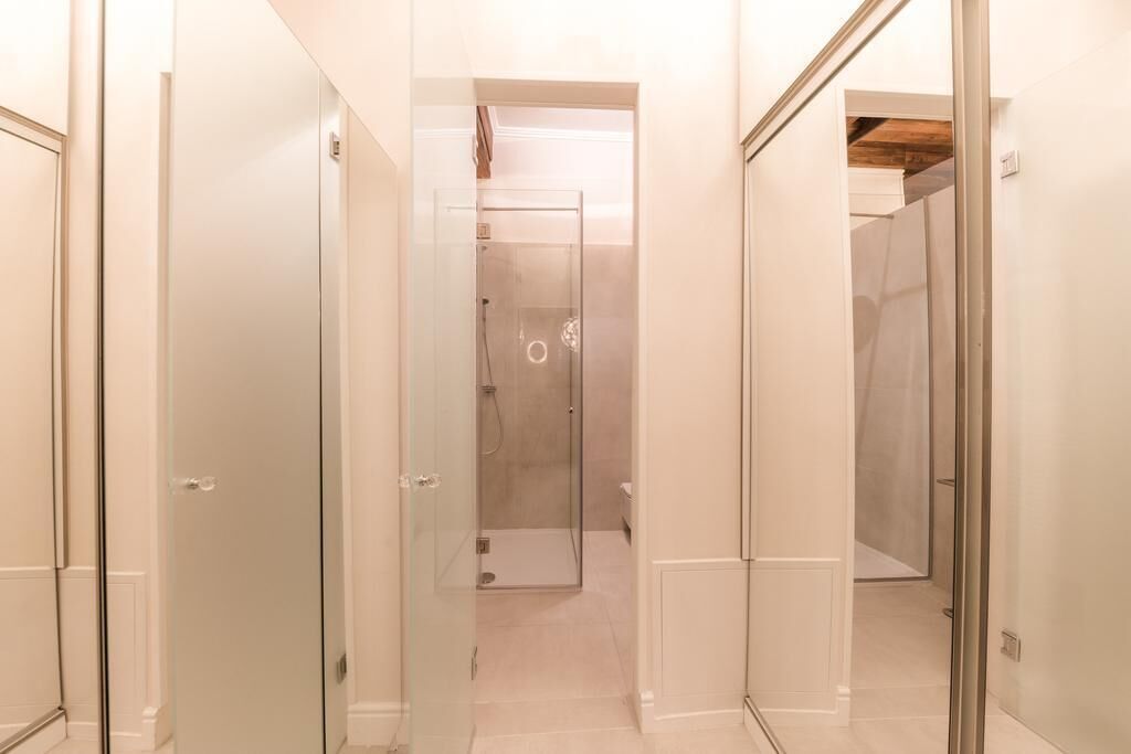 A hallway with glass doors leading to a shower area.