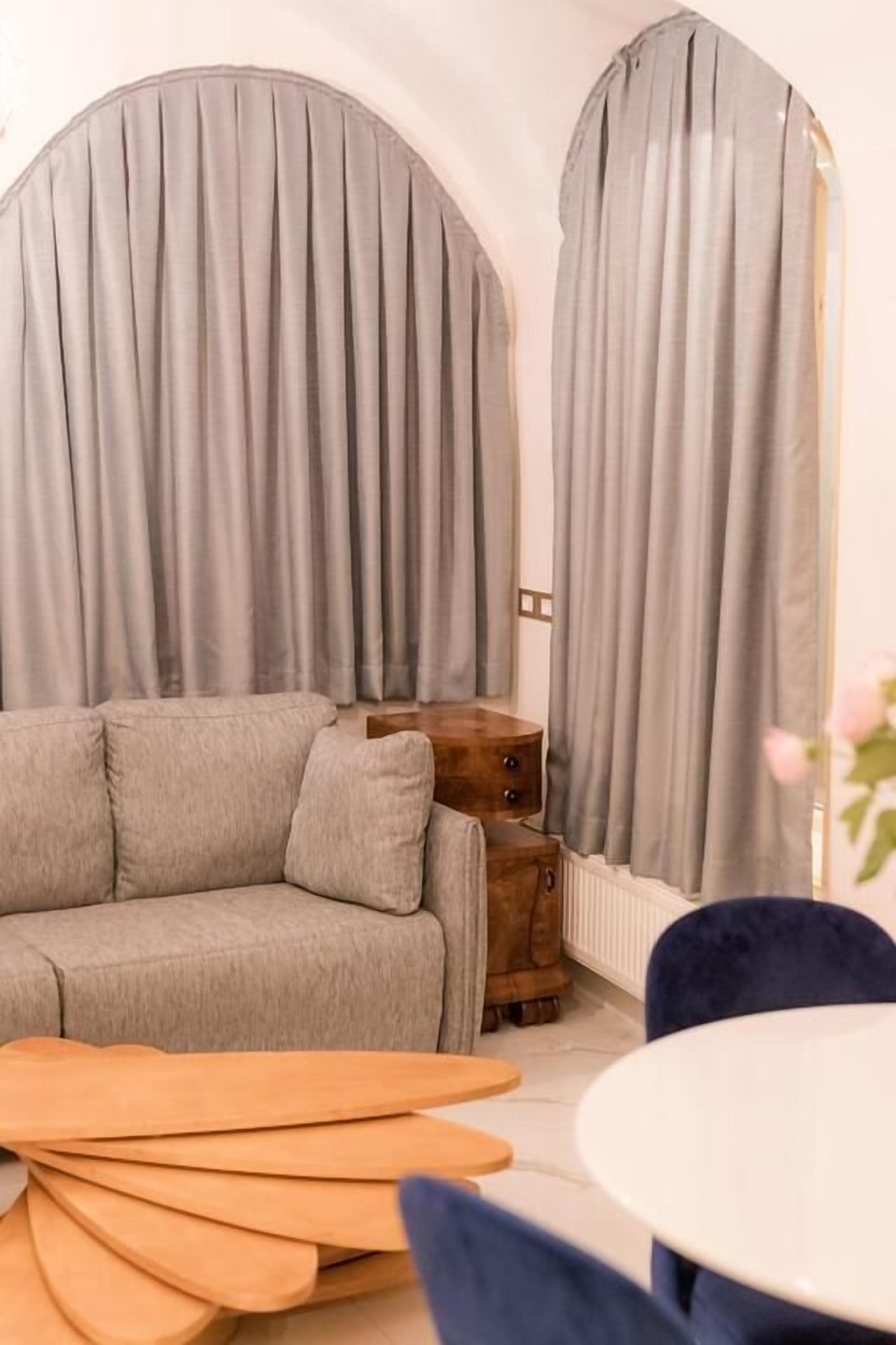 A modern living room with a grey sofa, wooden side table, and a round table.