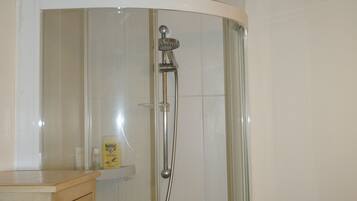 Een douche met een glazen deur, een houten kastje met potten, en een betegelde muur met een gele accentkleur.