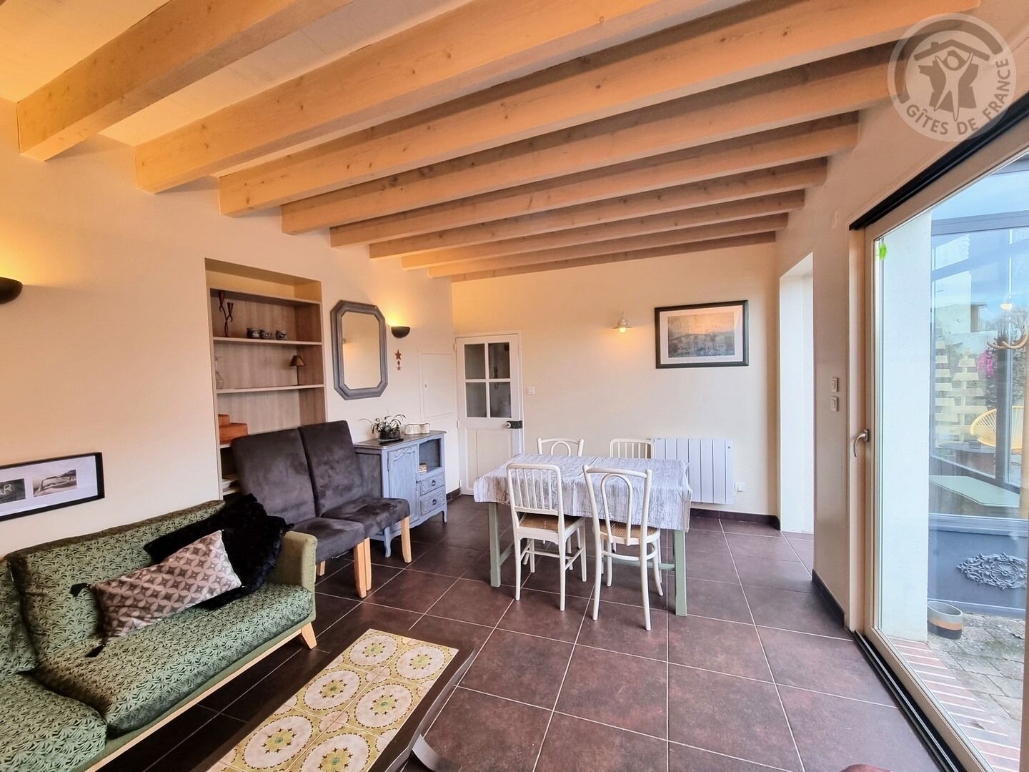 Un salon confortable avec un canapé, une table à manger et des chaises, ainsi qu’une grande fenêtre.