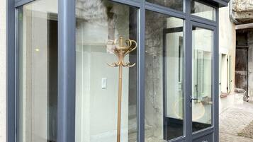 Een hoekconservatorium met grote glazen deuren en een donker frame, met decoratief metaalwerk op de onderste deuren.