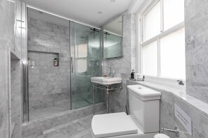 A modern bathroom with a glass-enclosed shower, a white sink, and a toilet. - Stylish 2 Bedroom Apartment Near Oxford Street (London)
