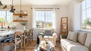Una sala de estar acogedora con un sofá, una mesa de centro y un comedor con sillas y una encimera de cocina.