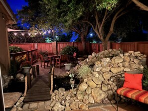 An outdoor patio area with a wooden deck, stone wall, and seating.