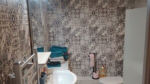 A bathroom with patterned tiles, a sink, a toilet, and a bathtub.