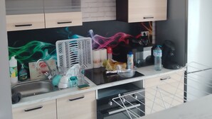 A modern kitchen with a white brick backsplash, black range hood, and stainless steel appliances.