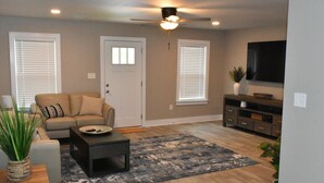 A living room with a beige sofa, a coffee table, a TV, and a ceiling fan. - Waterfront house with beautiful views of Perdido Bay facing Florida. (Elberta)