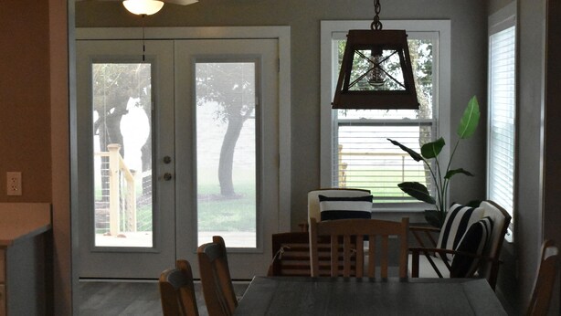A dining area with a table and chairs, a hanging light fixture, and a view through a door. - Waterfront house with beautiful views of Perdido Bay facing Florida. (Elberta)