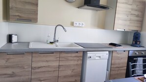 Een moderne keuken met een inbouw vaatwasser, een spoelbak met kraan en een koffiezetapparaat.