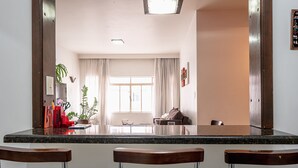 Une cuisine dotée d’un plan de travail en granit, de trois tabourets de bar, d’une fenêtre avec des rideaux et d’une plante.