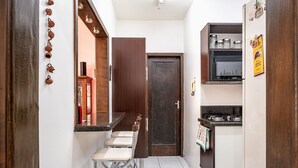 Une cuisine étroite avec une porte en bois foncé, un plan de travail avec une cuisinière et un petit coin bar avec des tabourets.